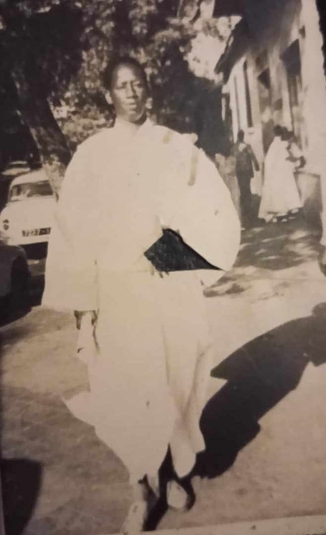 Homme en boubou blanc dans la rue — Cliché en noir et blanc : un homme en boubou blanc marchant dans une rue. Document de famille.